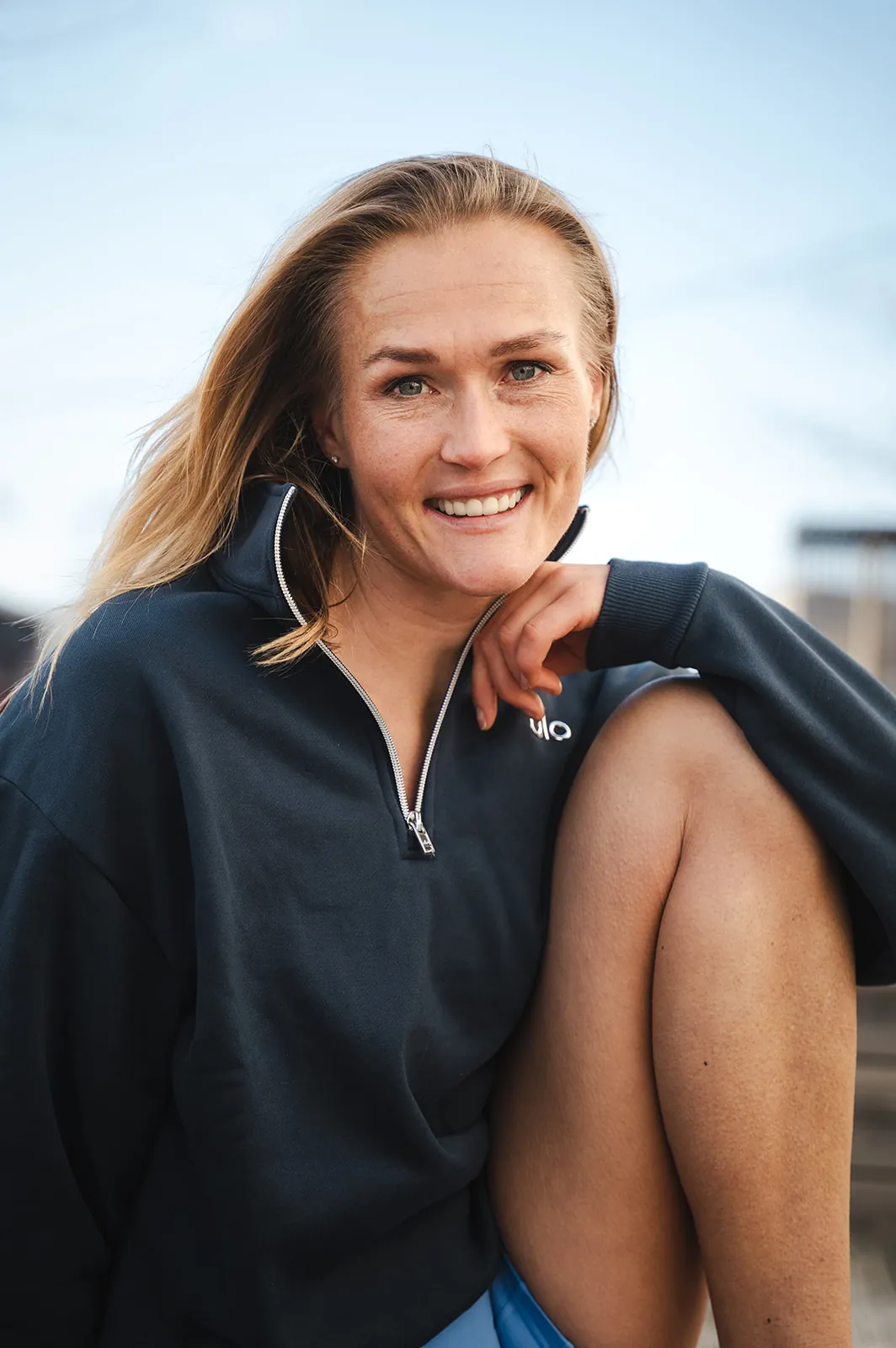 Christina Skei smiler, sittende utendørs i genser